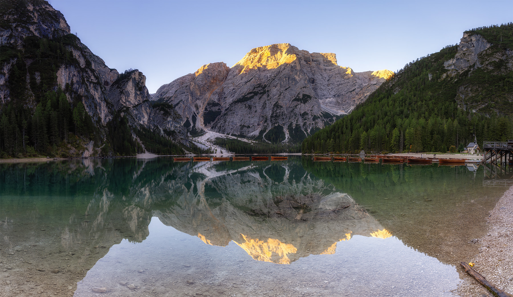 The golden peaks mirrored on the calm water The golden peaks mirrored on the calm water